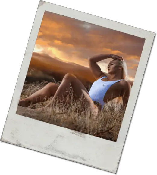 Blonde fitness model sitting under the orange sky in white bathing suit