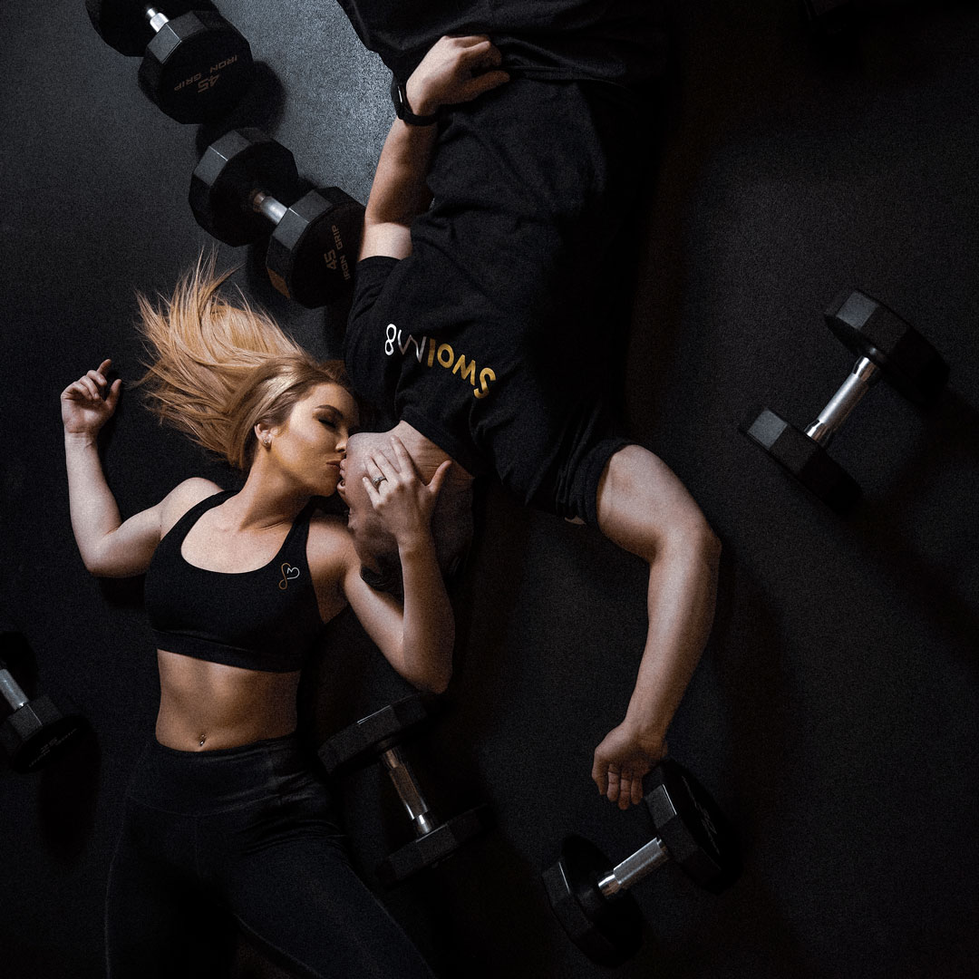 fitness couple lying on the ground with dumbbells kissing